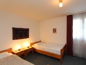 A hotel room with a single bed, bedside tables with lamps, a wall tapestry, a framed picture, and a window with curtains. - Las Vals B5 Appartement/Fewo, Bad, WC, 2 Schlafräume 3 Zimmerwohnung - 5 Betten by Interhome (Savognin)