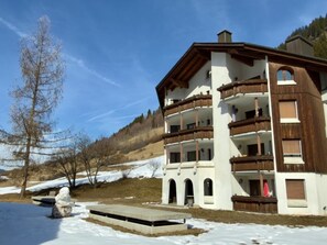 Ein mehrgeschossiges Gebäude mit Balkonen, einer Steintreppe und einem mit Schnee bedeckten Untergrund.