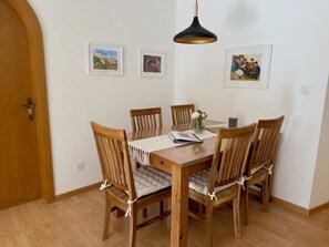 A dining area with a wooden table and chairs, a hanging pendant light, and framed pictures on the wall. - Cadras 14 Appartement/Fewo, Dusche oder Bad, WC, 2 Schlafräume by Interhome (Savognin)