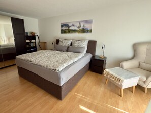 Una camera da letto con un letto grande, un comodino, una sedia e un quadro appeso al muro.