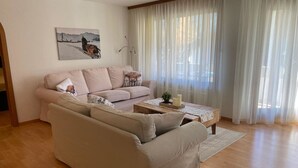 A living room with a beige sofa, a coffee table, and a painting on the wall. - Cadras 14 Appartement/Fewo, Dusche oder Bad, WC, 2 Schlafräume by Interhome (Savognin)