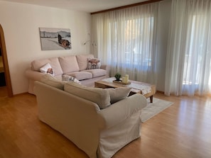 Ein Wohnzimmer mit einem beigefarbenen Sofa, einem Couchtisch und einem Bild an der Wand.