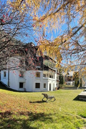 A two-story building with a balcony, surrounded by trees with autumn foliage. - Cadras 14 Appartement/Fewo, Dusche oder Bad, WC, 2 Schlafräume by Interhome (Savognin)