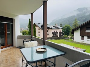 Ein Balkon mit Glastisch, einem weißen, flauschigen Kissen und einer Metallschale.