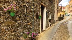 A stone building with a wooden bench, potted plants, and a narrow street. - A cool, comfortable, and beautiful apartment (Aritzo)