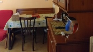 A dining area with a table and chairs, a wooden cabinet, and a painting on the wall. - A cool, comfortable, and beautiful apartment (Aritzo)