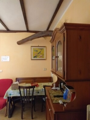 Ein Essbereich mit Tisch, Stühlen, einem Holzschrank und einem Bild an der Wand.