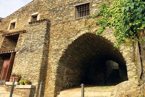 A stone building with a large arched doorway and a small window. - A cool, comfortable, and beautiful apartment (Aritzo)
