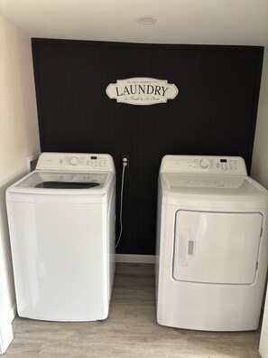 Une buanderie équipée de deux machines à laver à chargement frontal, avec une pancarte au-dessus de la porte indiquant « BUANDERIE ».