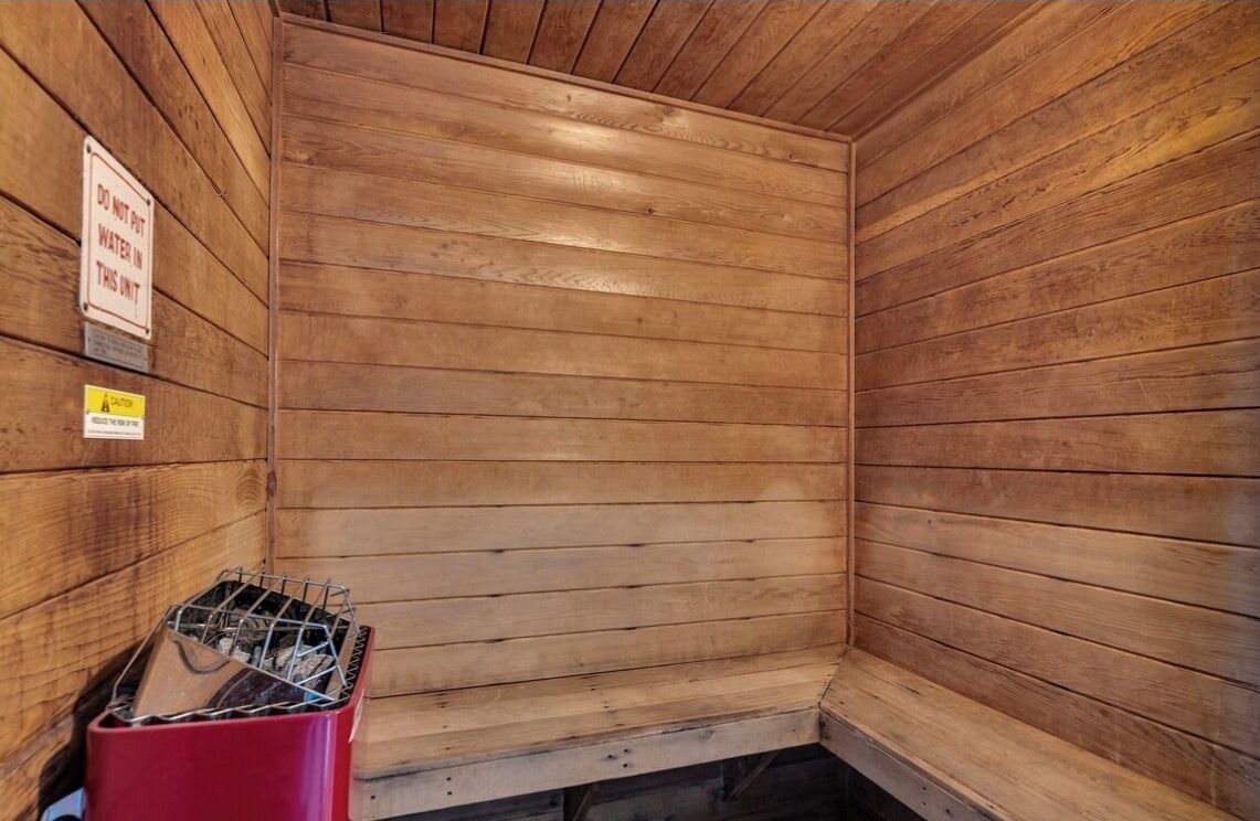 A wooden cabin interior with a red trash bin and a sign instructing not to put water in the unit.