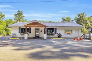 A building with a covered entrance, a sign indicating a food and beer service, and a parking area with marked spaces.