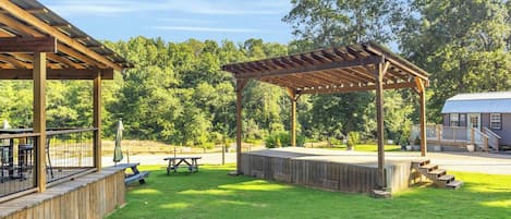 Un espacio al aire libre cubierto con mesas de picnic y una terraza de madera.