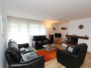 A living room with two black leather sofas, a glass coffee table, a flat-screen TV, and a fireplace. - Las Vals B11 Appartement/Fewo, Bad, WC, 3 Schlafräume by Interhome (Savognin)