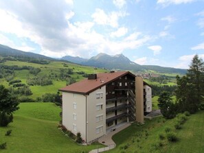 A multi-story building with a sloped roof, surrounded by lush green fields and mountains in the background. - Las Vals B11 Appartement/Fewo, Bad, WC, 3 Schlafräume by Interhome (Savognin)