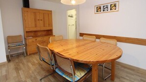 Een eetruimte met een ronde houten tafel, vier stoelen, een houten kast en een hanglamp.