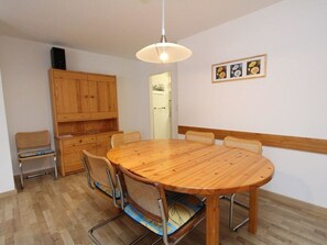 A dining area with a round wooden table, four chairs, a wooden cabinet, and a hanging light fixture. - Las Vals B11 Appartement/Fewo, Bad, WC, 3 Schlafräume by Interhome (Savognin)