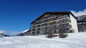 Een hotel met meerdere verdiepingen en balkons, met een besneeuwde berg op de achtergrond.