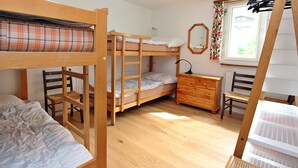 Ein Schlafsaalzimmer mit Etagenbetten, einem Schminktisch und einem Fenster mit Vorhängen.