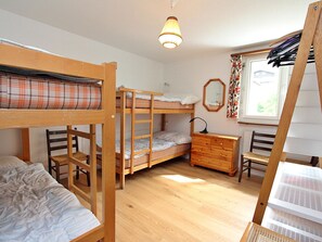 Ein Schlafsaalzimmer mit Etagenbetten, einem Schminktisch und einem Fenster mit Vorhängen.