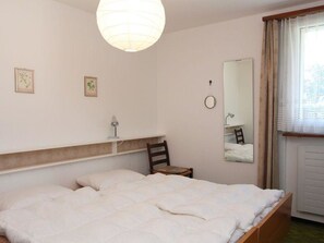 A bedroom with a bed, a chair, a bedside table, a lamp, and a mirror. - Las Vals E10 Appartement/Fewo, Bad, WC, 2 Schlafräume 3 Zimmerwohnung - 6 Betten by Interhome (Savognin)