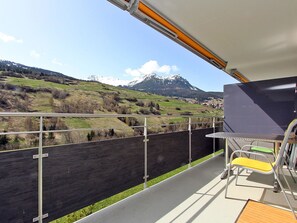 A balcony with a view of a mountainous landscape, a table with chairs, and a large window. - Las Vals E03 Appartement/Fewo, Dusche, WC, 2 Schlafräume by Interhome (Savognin)