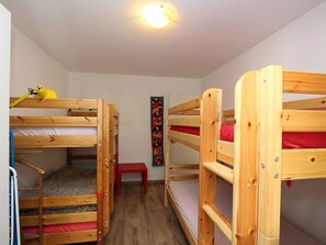 A room with three wooden bunk beds, a red stool, and a colorful wall hanging. - Las Vals E03 Appartement/Fewo, Dusche, WC, 2 Schlafräume by Interhome (Savognin)