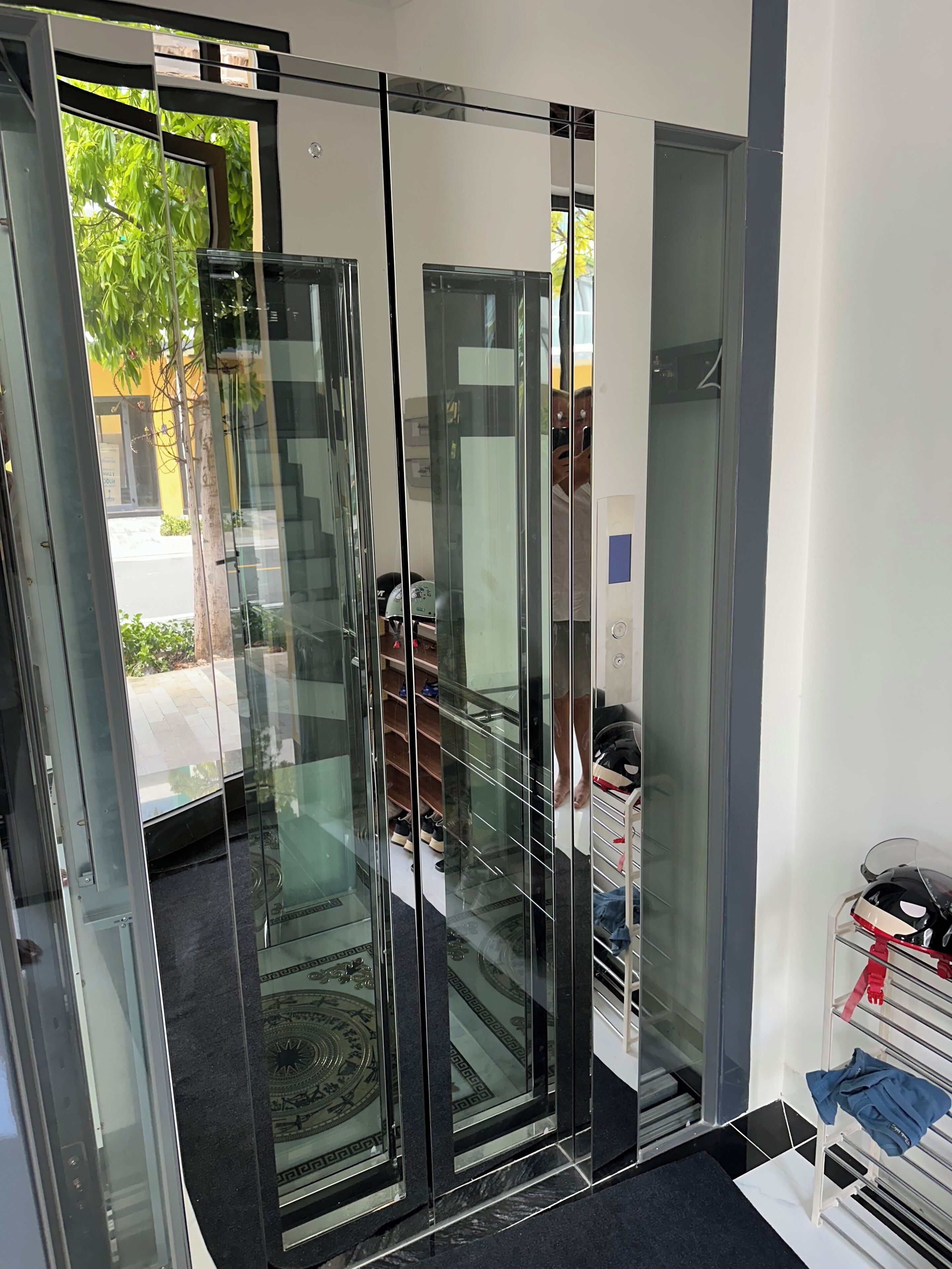 A modern interior with a glass door leading to a hallway, a shoe rack, and a motorcycle.