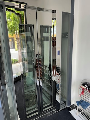 A modern interior with a glass door leading to a hallway, a shoe rack, and a motorcycle.