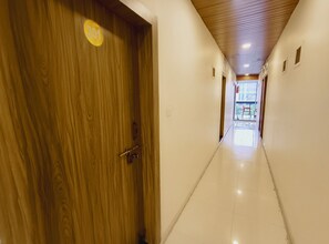 A corridor with a wooden door marked '301' and a view of an outdoor area with chairs. - Maa Kripa Hotel (Ujjain)