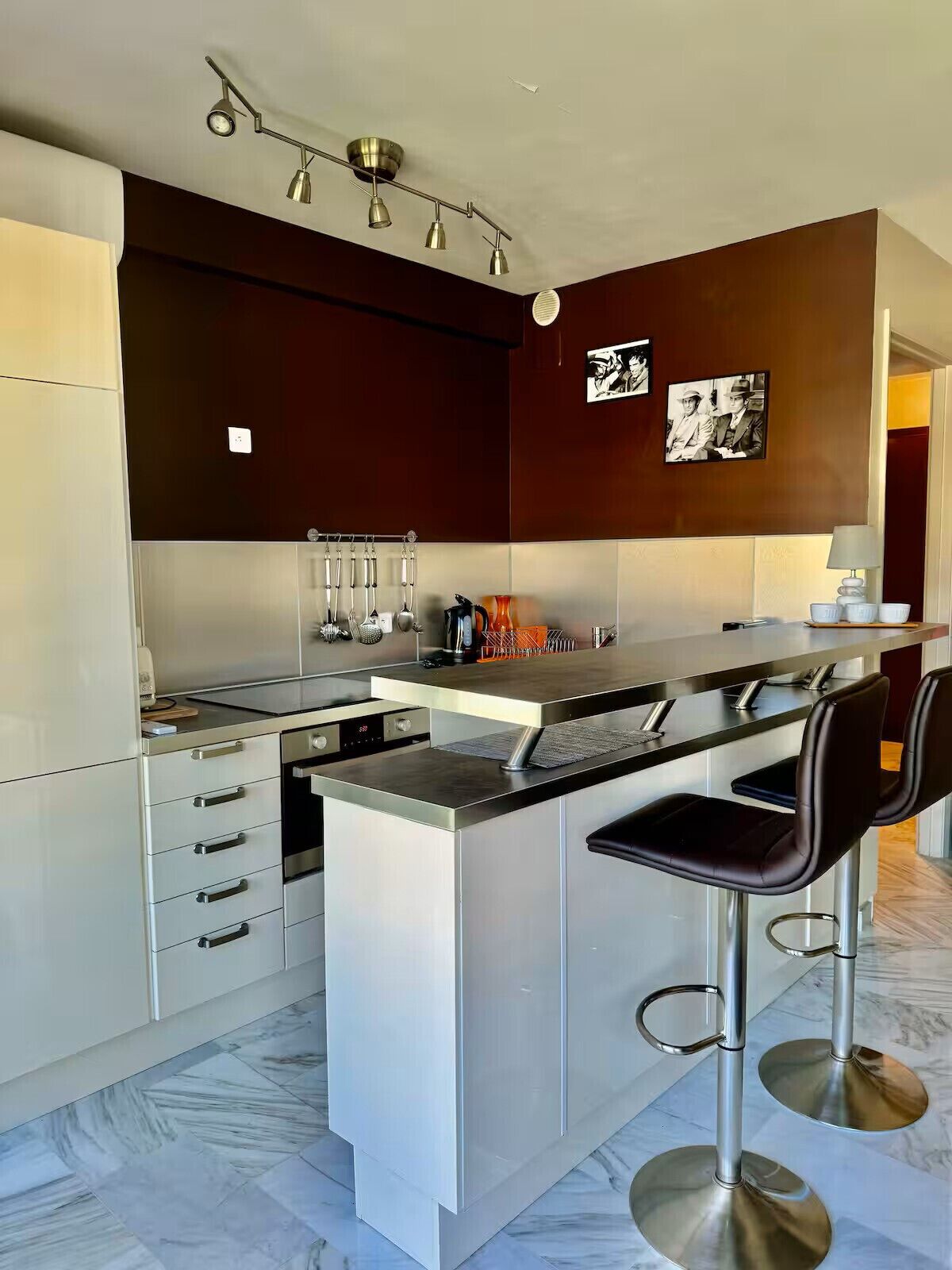 A modern kitchen with a central island, bar stools, and a pendant light fixture.