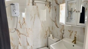 A bathroom with a toilet, a sink, and a shower. - The Nook in Rye Town Centre (East Sussex)