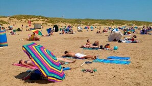 A beach with people sunbathing, tents, and colorful umbrellas. - The Nook in Rye Town Centre (East Sussex)