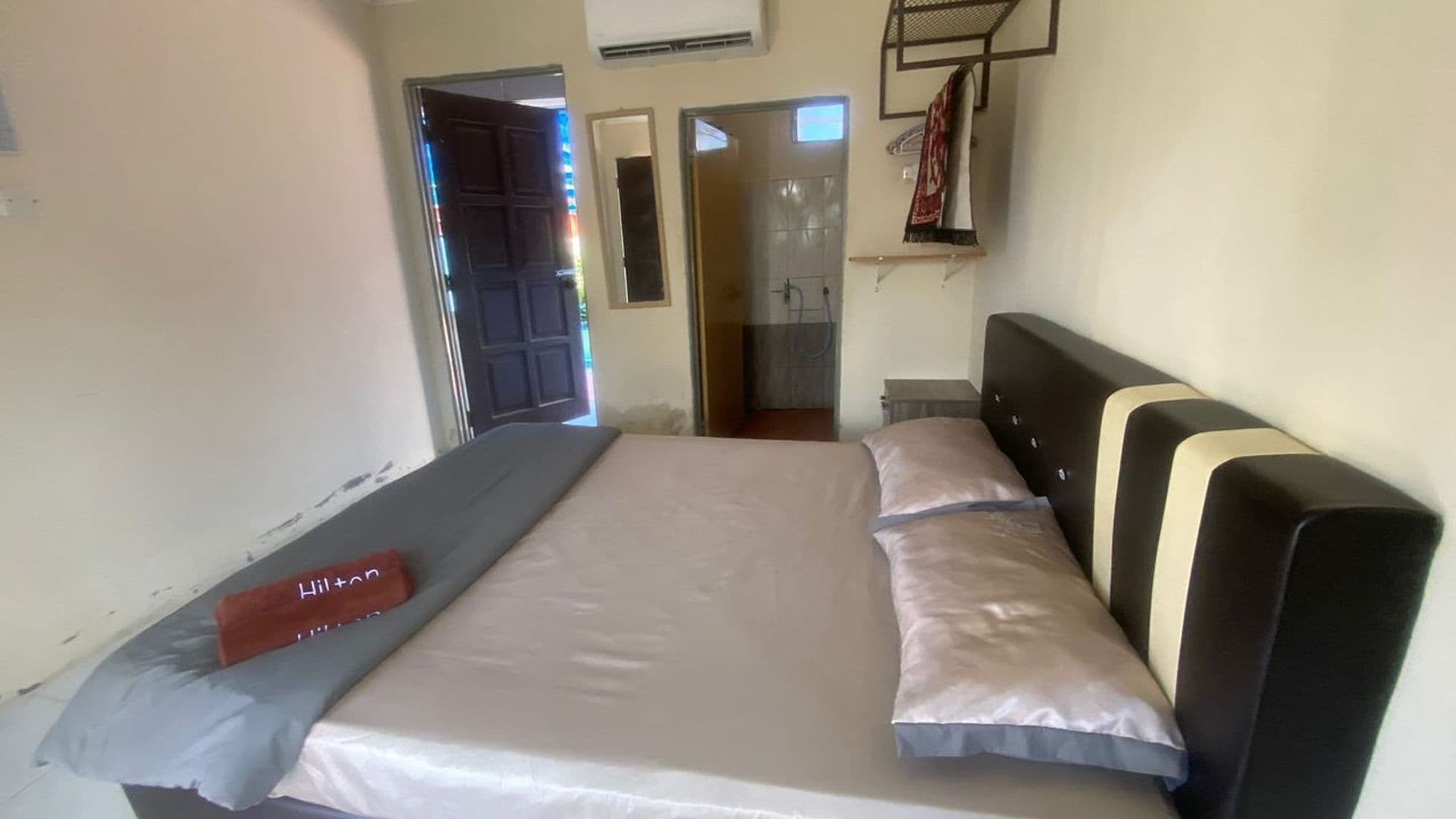 Un dormitorio con cama, cabecera y puerta que da a un baño.
