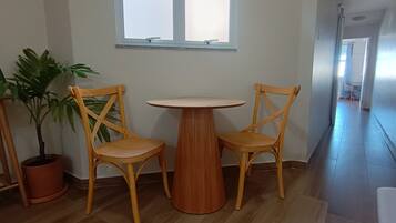 A room with a wooden table and two chairs, a potted plant, and a window.