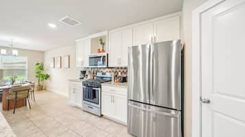 A modern kitchen with white cabinetry, stainless steel appliances, and a dining area with a table and chairs.