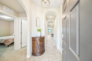 A hallway with a bed, a wooden cabinet, and a door. - Sleeps 7~GarageAccess~Coffee Bar~Patio w/ FirePit (Bixby)