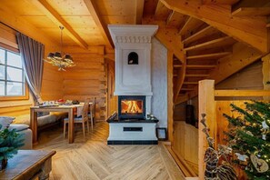 Ein gemütliches Blockhaus-Interieur mit Kamin, Holzmöbeln und einem Essbereich.