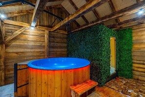 Ein Holzblockbau-Innenraum mit Whirlpool, Holzwänden und einer grünen Wand.