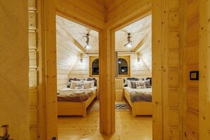 Habitación con espejos, dos camas, paredes de madera y techo inclinado.