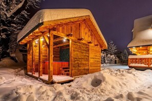 A wooden cabin with a snow-covered roof, surrounded by snow.