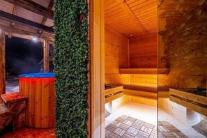 Een sauna met houten wanden, een bankje, een zwembad en een groene wand.