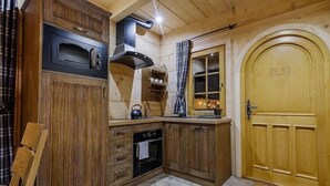 Ein Holzinnenraum mit eingebautem Ofen, einer Tür mit Herzmotiv und einem fensterbepflegten Fenster.