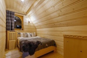 A wooden cabin bedroom with a bed, a window with curtains, and a small table. - Two-story mountain-style house, sauna, jacuzzi (Murzasichle)