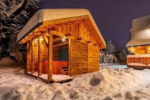 Een houten hutje met een overdekte veranda, omringd door sneeuw.