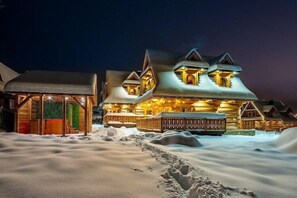 A snow-covered lodge with a wooden exterior and a well-lit entrance. - Two-story mountain-style house, sauna, jacuzzi (Murzasichle)