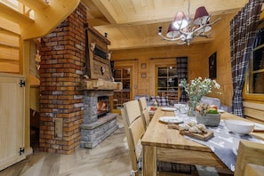 A cozy interior with a stone fireplace, wooden furniture, and a chandelier.