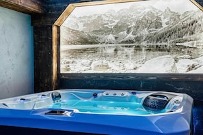 Ein Whirlpool mit Blick auf eine verschneite Berglandschaft.