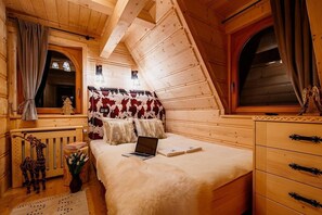 Quarto de cabana de madeira aconchegante, com uma cama, um laptop, cômoda e janela com cortinas.