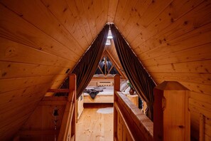 A wooden attic bedroom with a sloped ceiling, a bunk bed, and a small window. - Comfortable mountain-style house with a SPA area (Murzasichle)