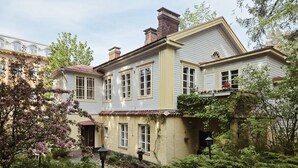 Een herenhuis met tuin, een zichtbare schoorsteen en een raam met bloembak.